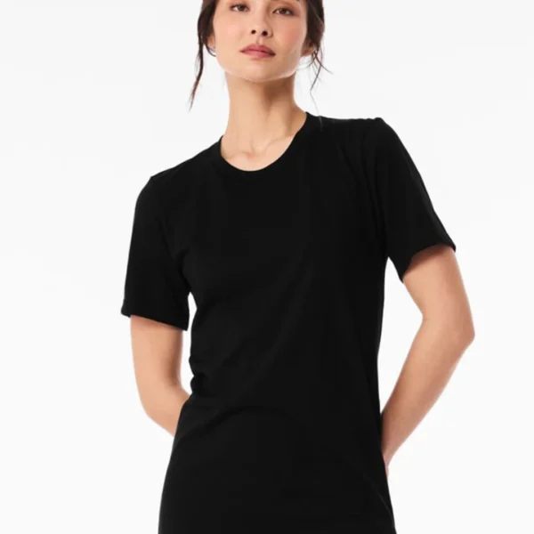Model wearing a plain black crew-neck t-shirt, standing against a white background with hands behind her back.