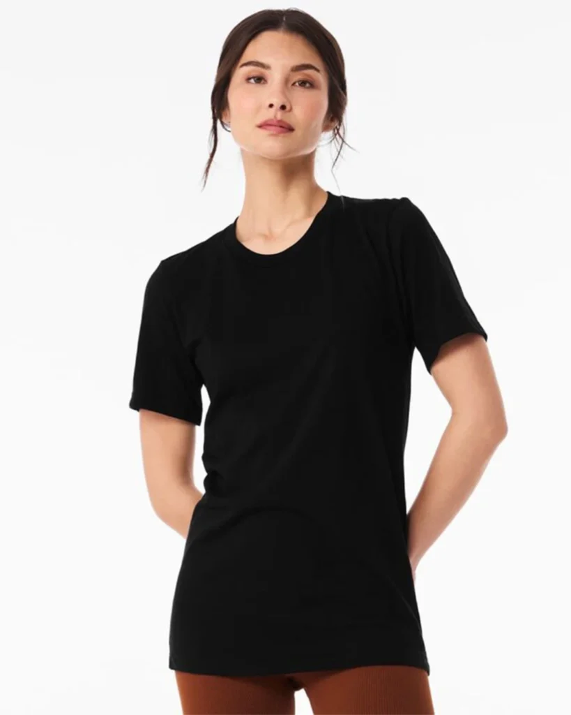 Model wearing a plain black crew-neck t-shirt, standing against a white background with hands behind her back.